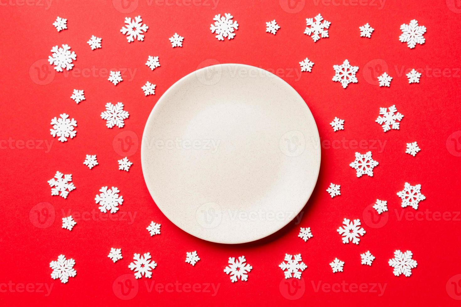 Top view of empty plate surrounded with snowflakes on colorful background. New Year dinner concept photo