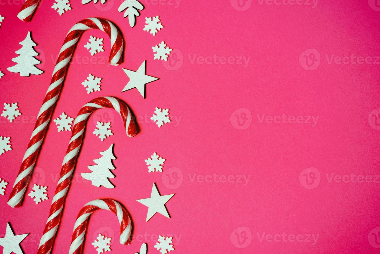 Christmas candy cane lied evenly in row on pink background with decorative snowflake and star. Flat lay and top view photo