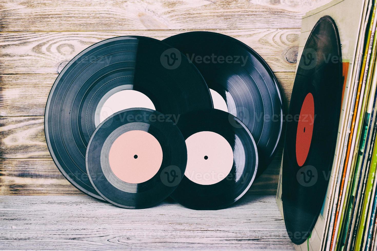 Retro styled image of a collection of old vinyl record lp's with sleeves on a wooden background with Copy space top view toned photo