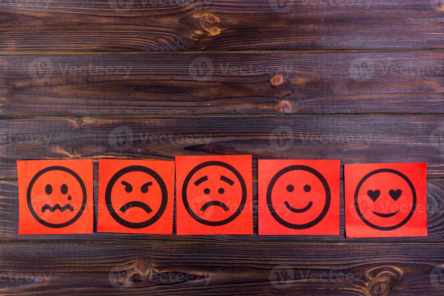 Red paper notes with happy, joy, anger, laughter and sad faces on blackboard. Vignette photo