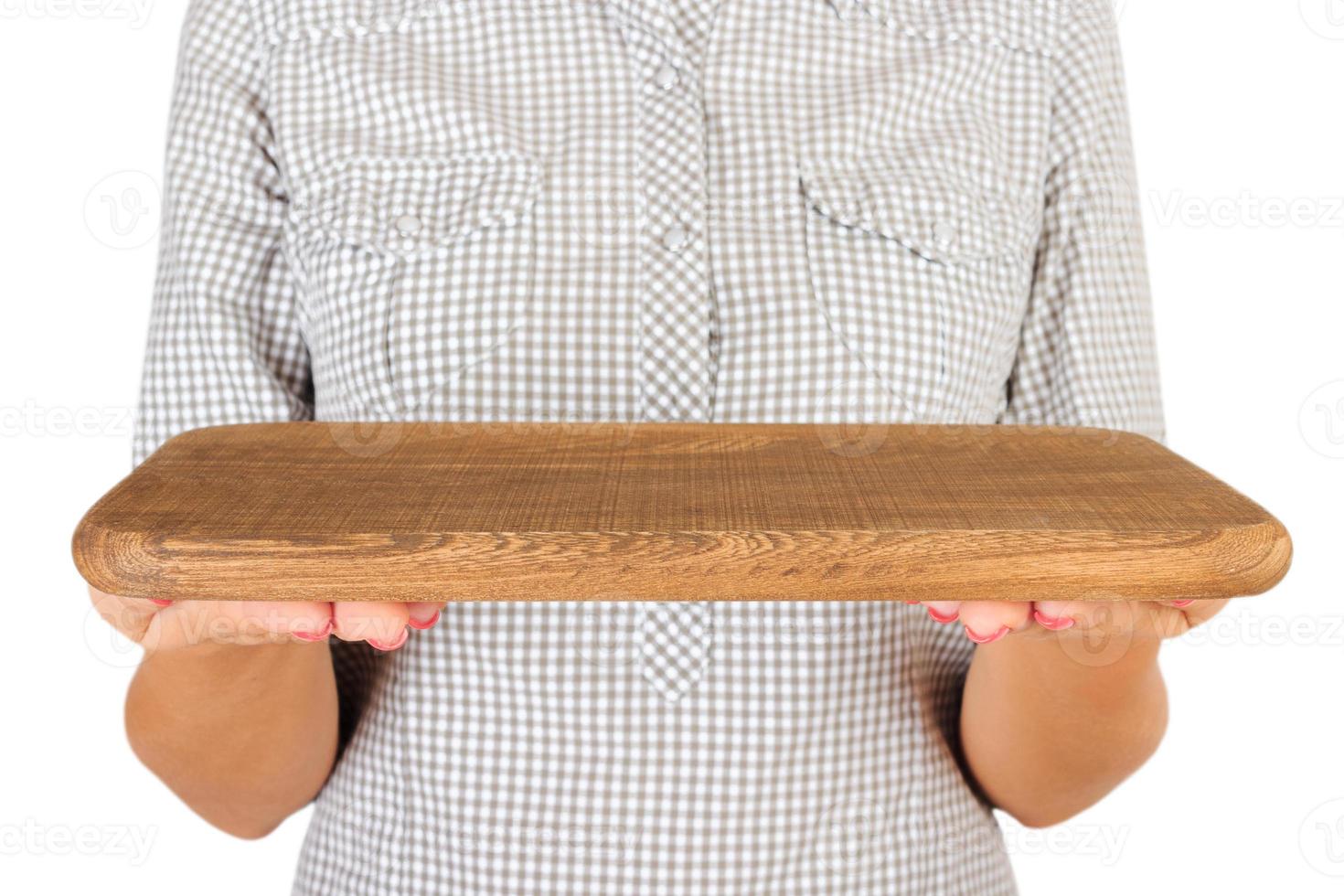 la chica de la camisa a cuadros sostiene un plato rectangular de madera vacío frente a ella. mano de mujer sostenga el plato vacío para su diseño. vista en perspectiva, aislada sobre fondo blanco foto