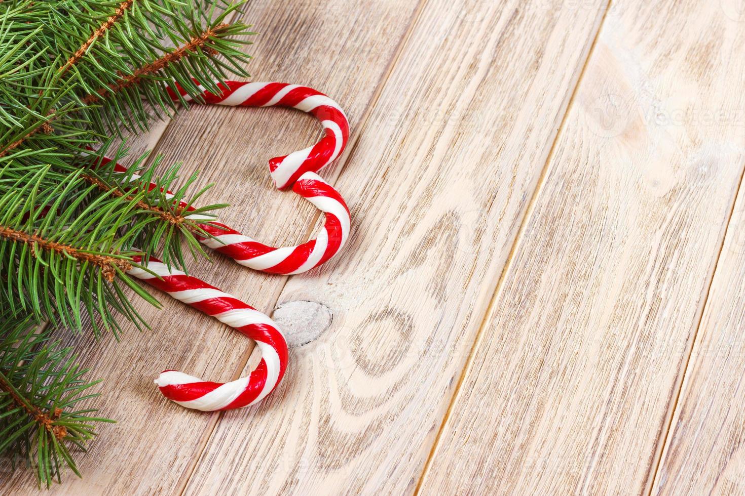 Christmas tree branch and candy cane on a wooden table or board for background. New year theme. Space for text photo