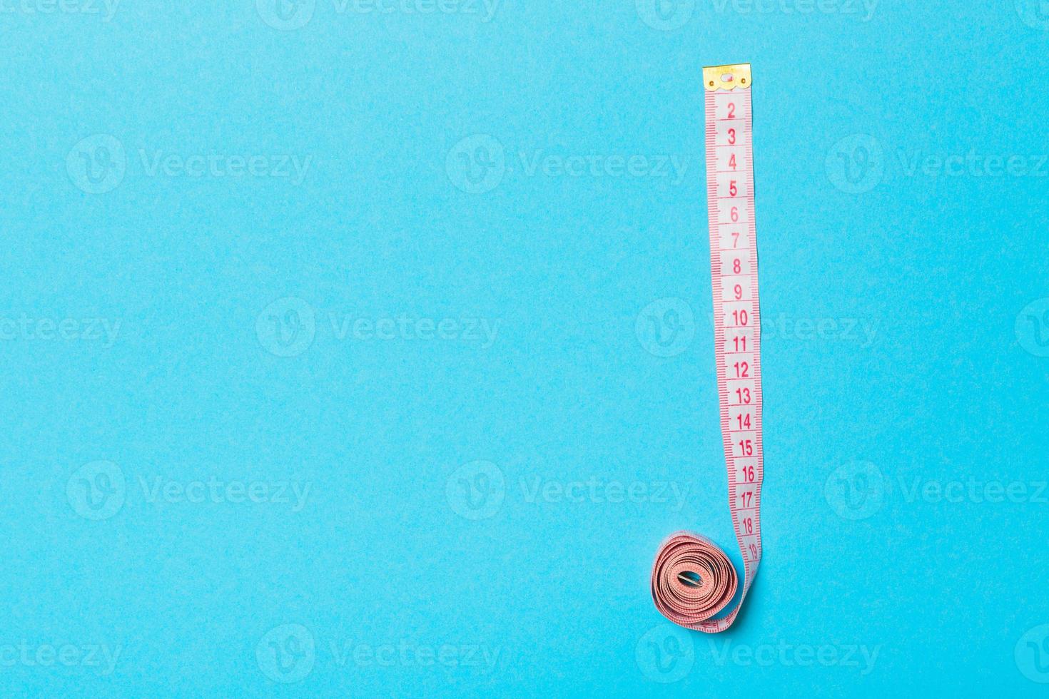 Frame made of measuring tape on blue background. Top view of sewing concept. Slim waist concept with empty space for your design photo