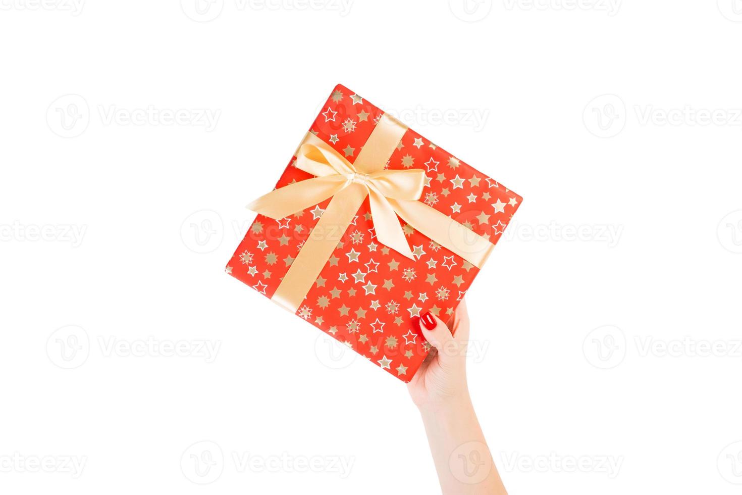 Woman hands give wrapped Christmas or other holiday handmade present in red paper with Gold ribbon. Isolated on white background, top view. thanksgiving Gift box concept photo