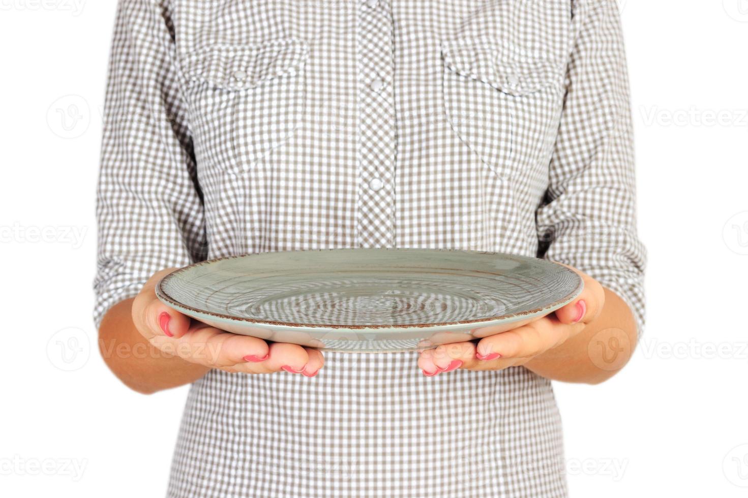 la chica de la camisa a cuadros sostiene un plato verde redondo vacío frente a ella. mano de mujer sostenga el plato vacío para su diseño. vista en perspectiva, aislada sobre fondo blanco foto