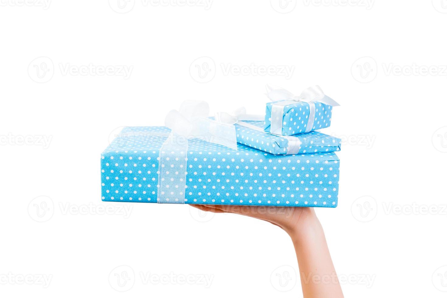 Woman hands give wrapped set of Christmas or other holiday handmade present in blue paper with white ribbon. Isolated on white background, top view. thanksgiving Gift box concept photo