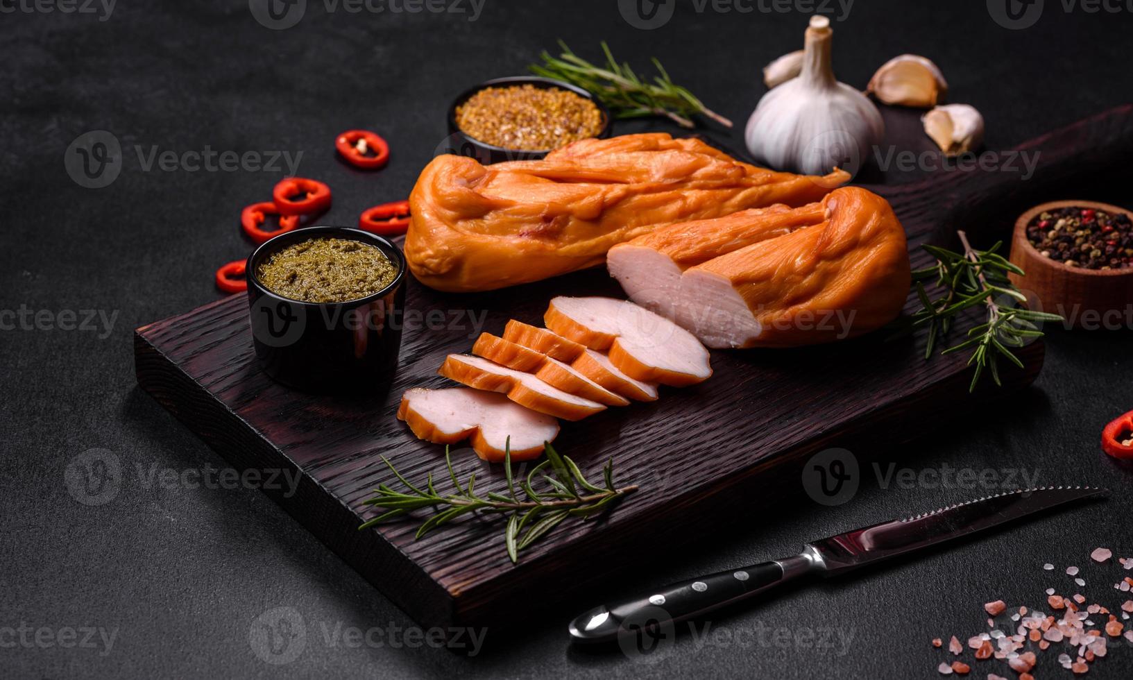 sabroso filete ahumado de pechuga de pollo con especias y hierbas en una tabla de cortar de madera foto