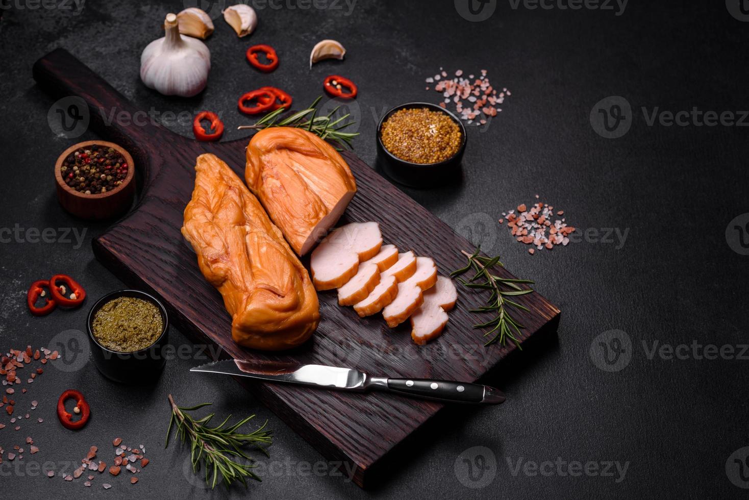 Tasty smoked fillet of chicken breast with spices and herbs on a wooden cutting board photo