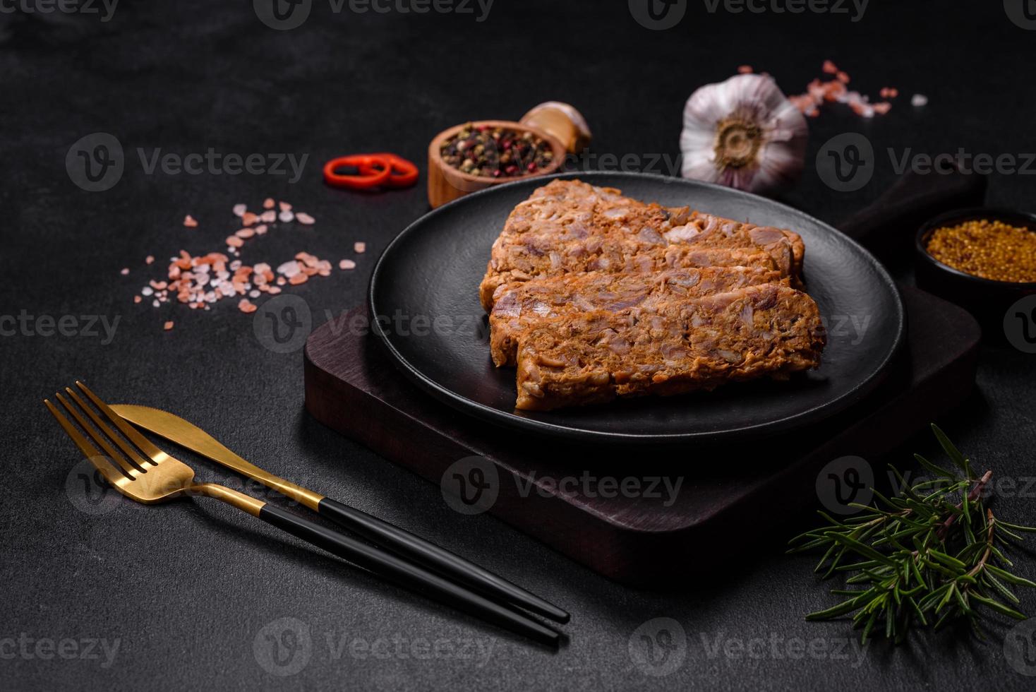 Tasty meat brawn or roll on a wooden cutting board with spices and herbs photo