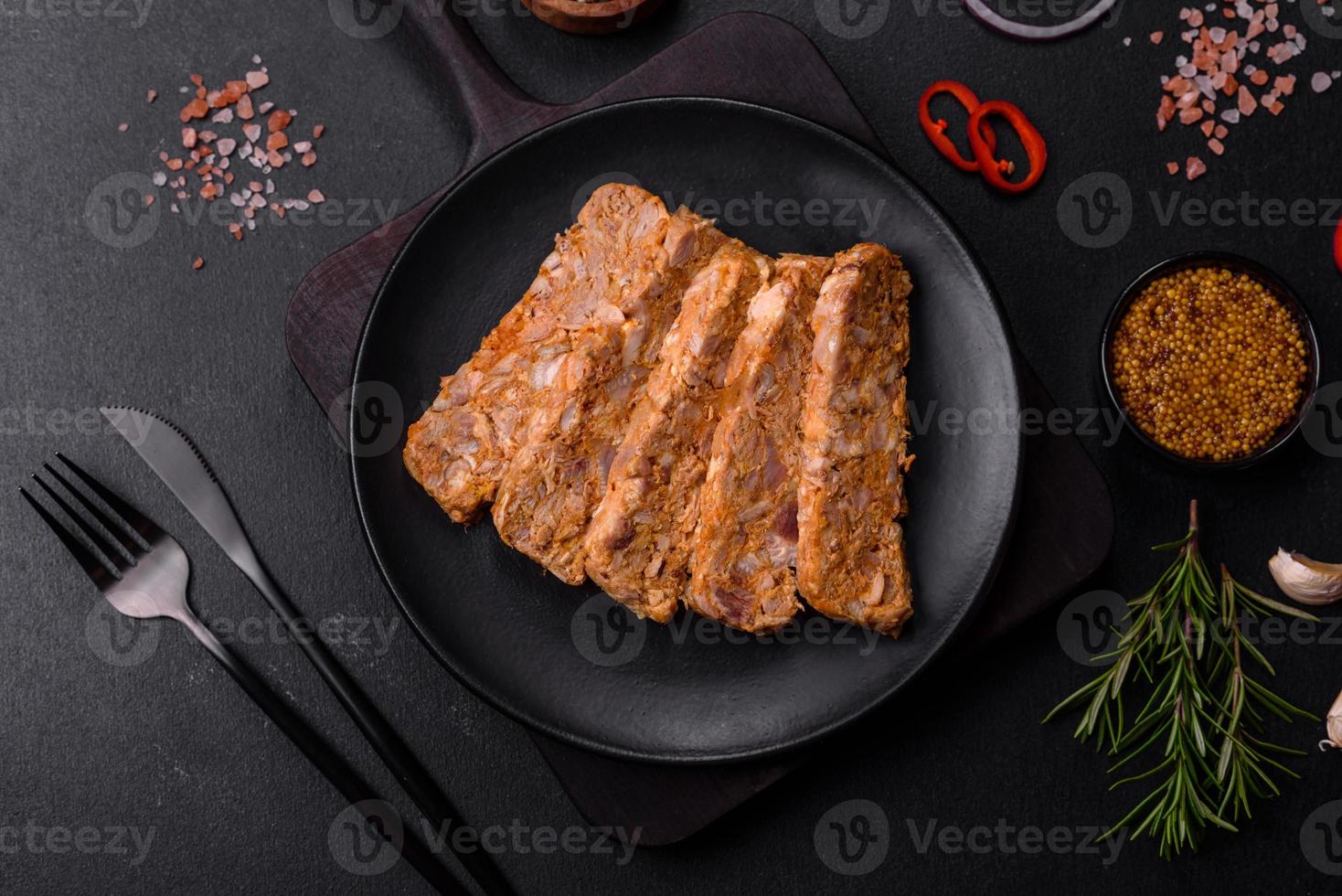 Tasty meat brawn or roll on a wooden cutting board with spices and herbs photo