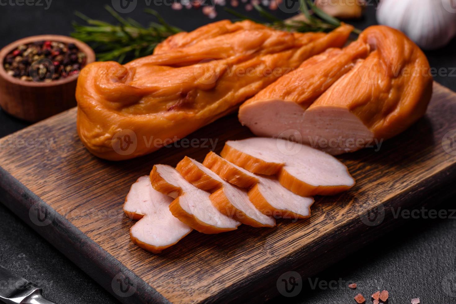 sabroso filete ahumado de pechuga de pollo con especias y hierbas en una tabla de cortar de madera foto