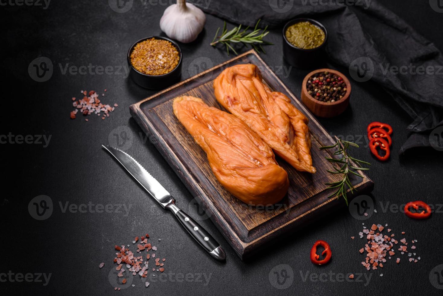 sabroso filete ahumado de pechuga de pollo con especias y hierbas en una tabla de cortar de madera foto