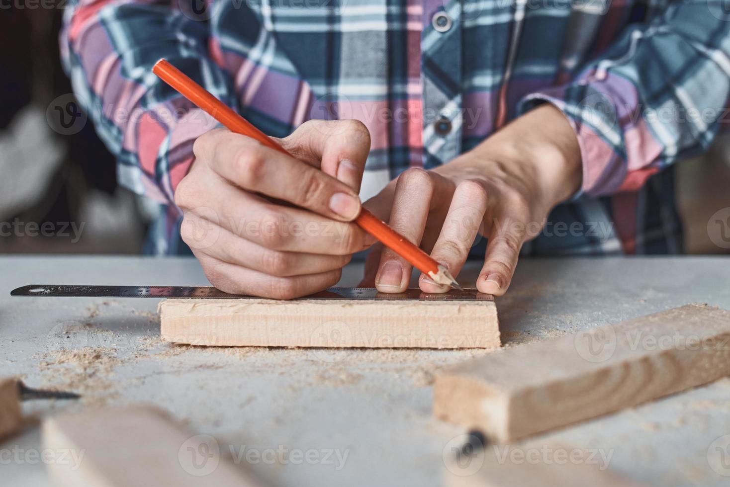 Carpenter hands taking measurement with a pencil of wooden plank. photo