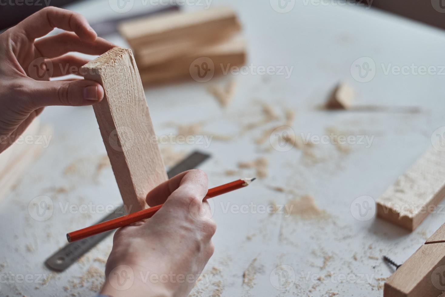 Carpenter hands taking measurement with a pencil of wooden plank. photo