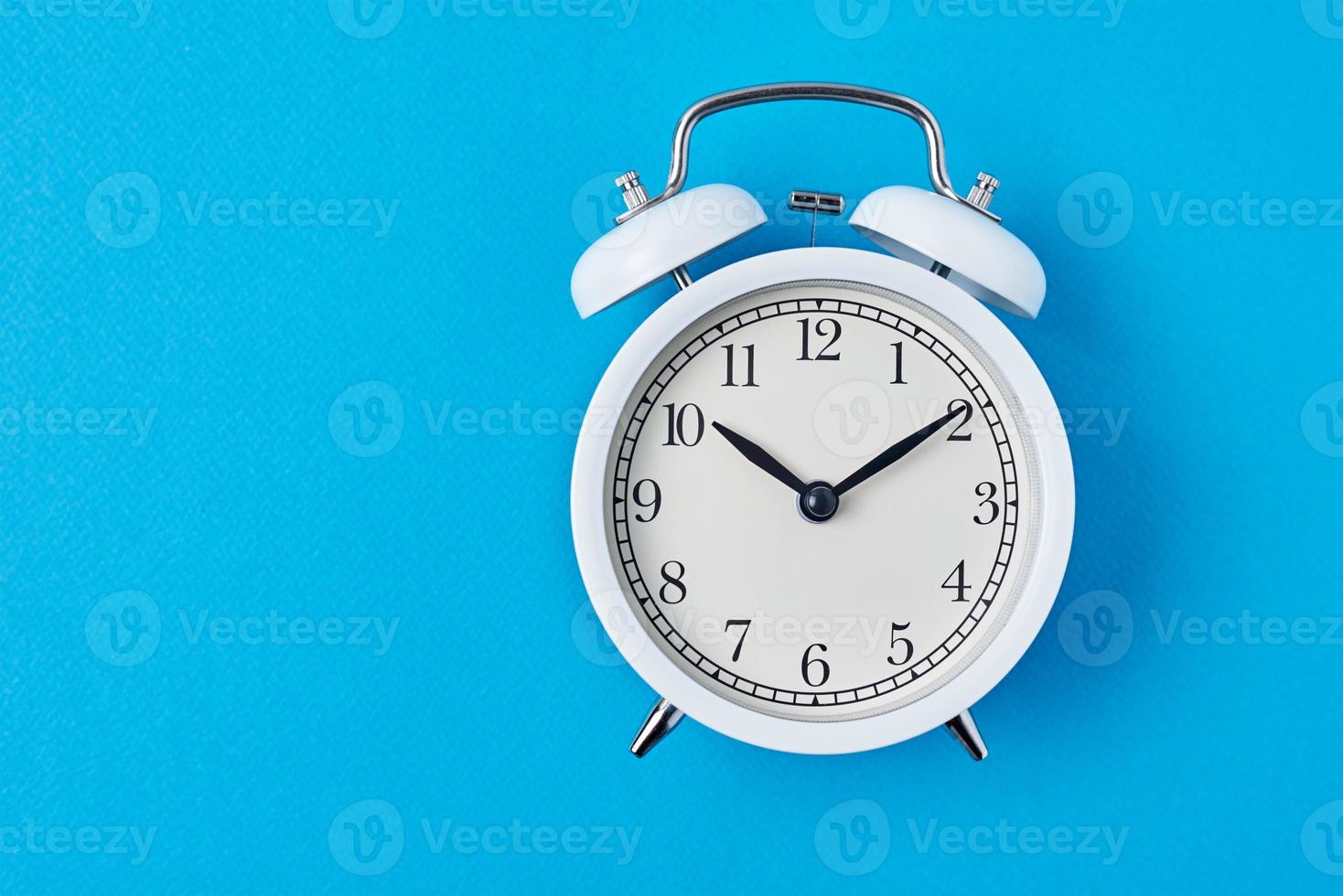 Vintage white alarm clock on the blue backround with copy space. Time concept photo