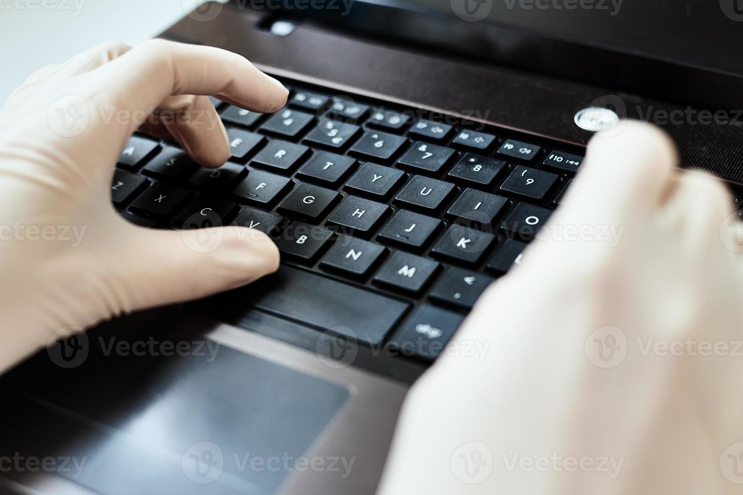 Hands in gloves typing on the laptop keyboard. Virus protection concept photo