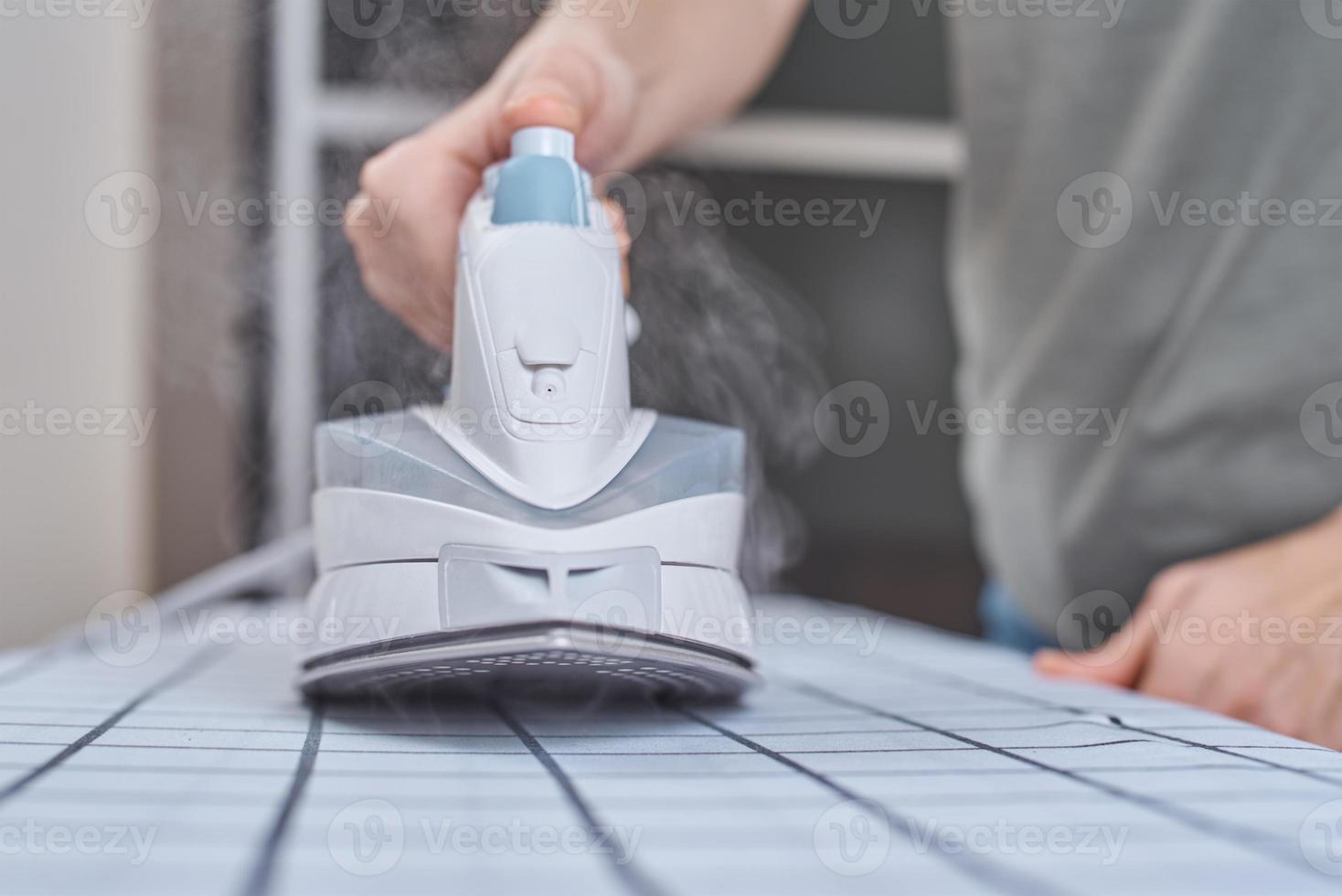 mujer planchando ropa en la tabla de planchar con plancha moderna foto