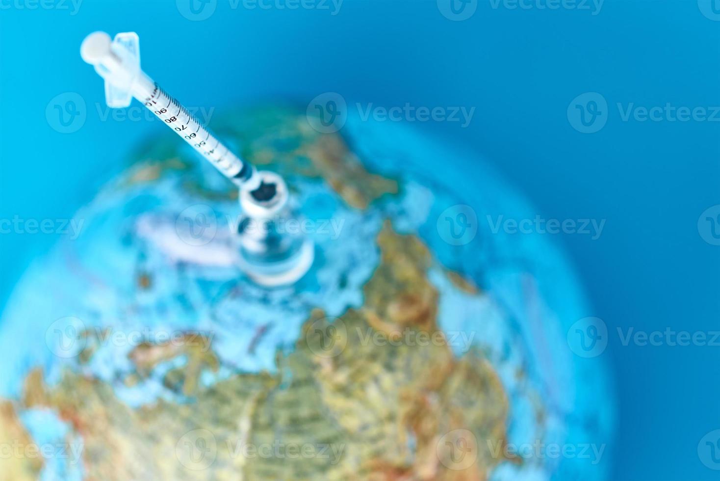 Medical syringe and ampoule with a medicine against Earth globe photo