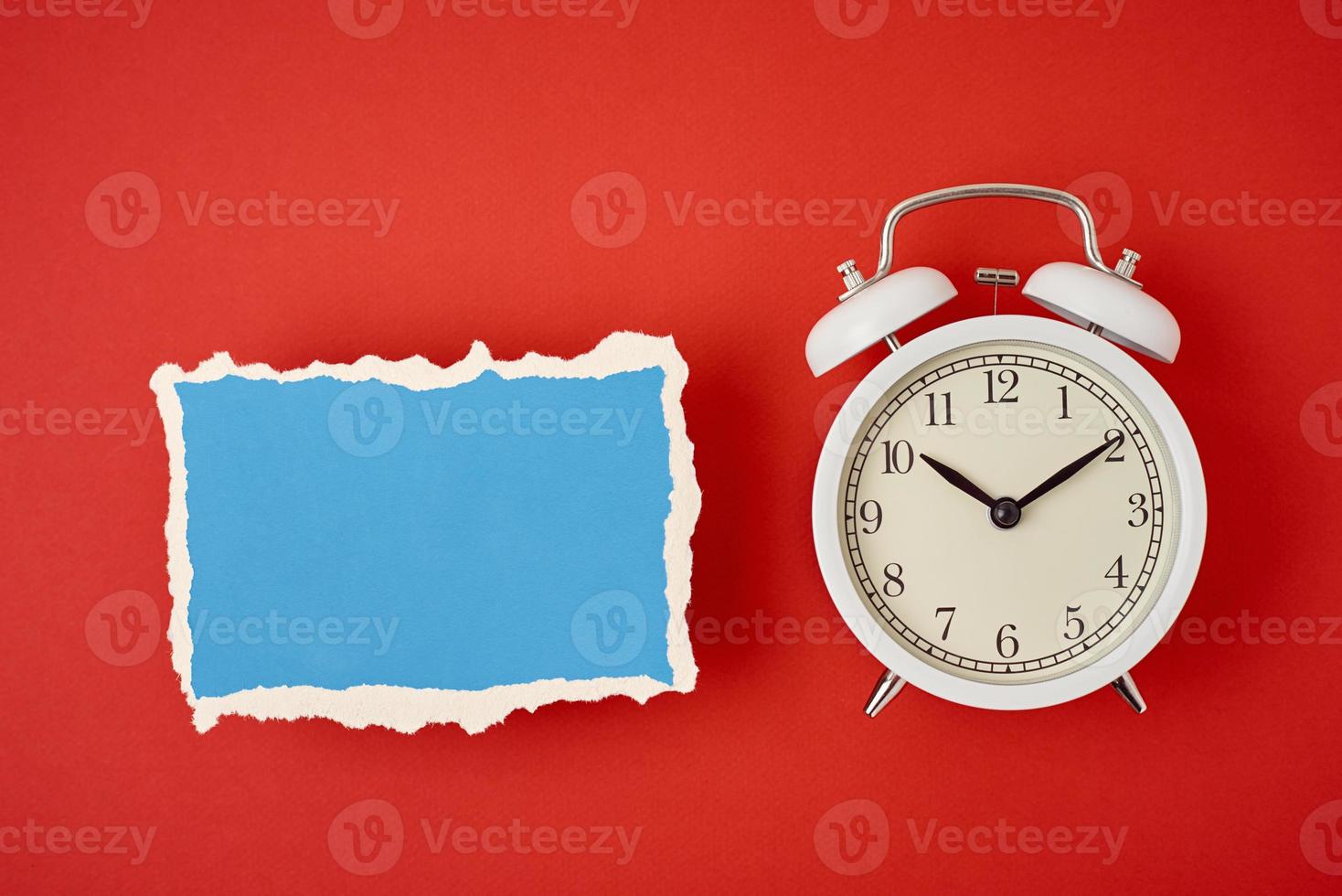 White vintage classic alarm clock with bells and empty torn paper sheet photo