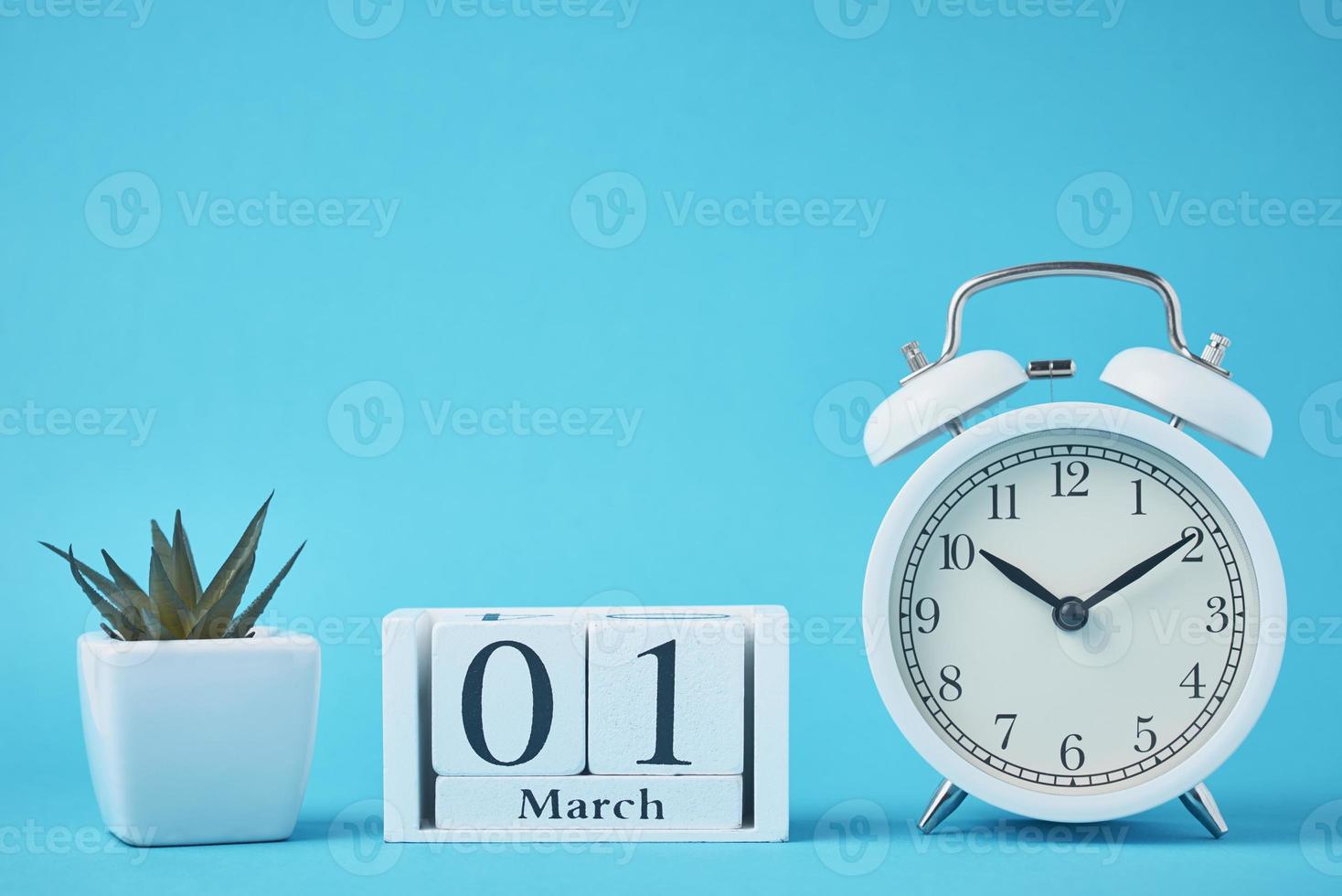 White retro alarm clock with bells and wooden calendar blocks with date 1 march photo