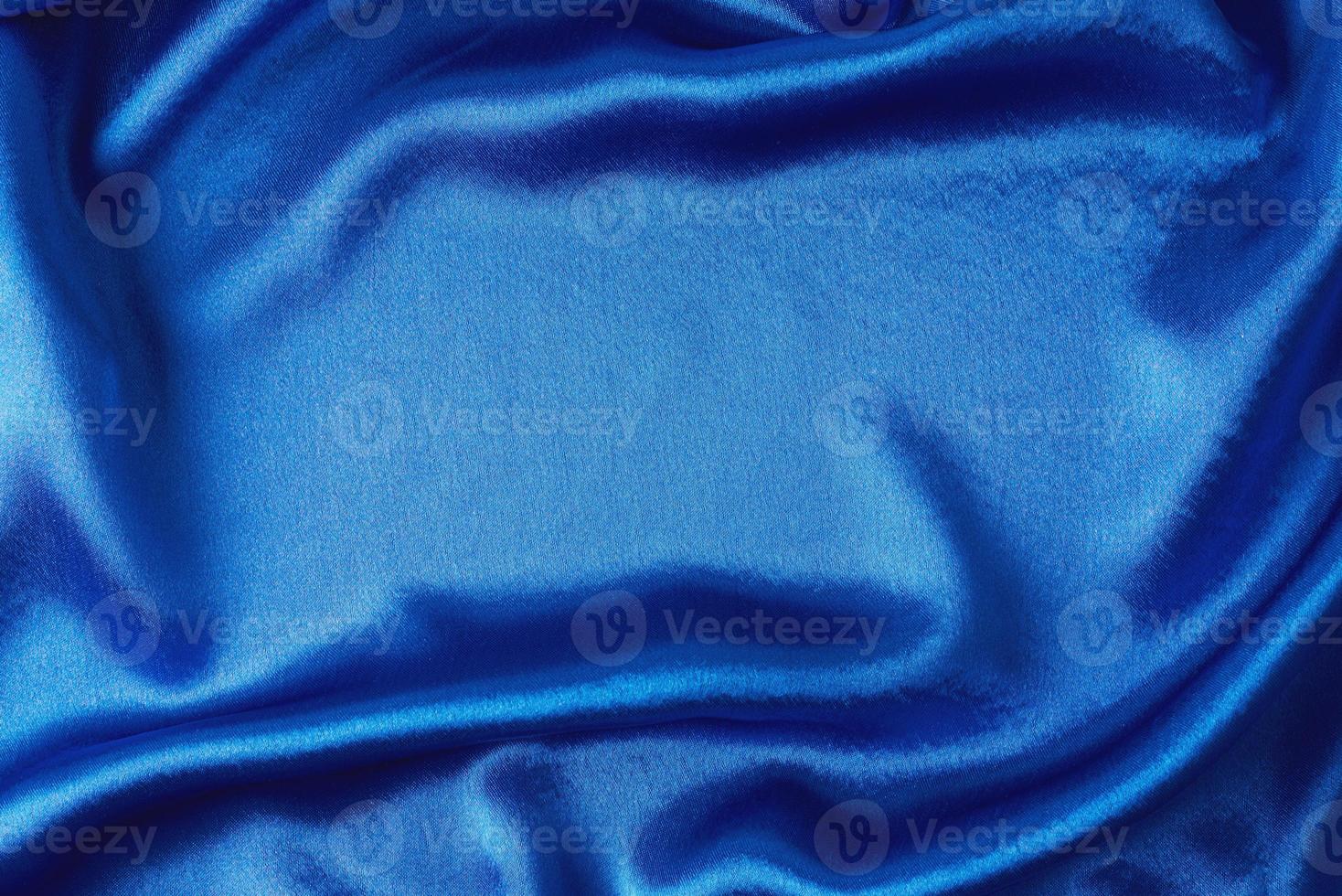 Blue silk background with a folds. Abstract texture of rippled satin surface photo