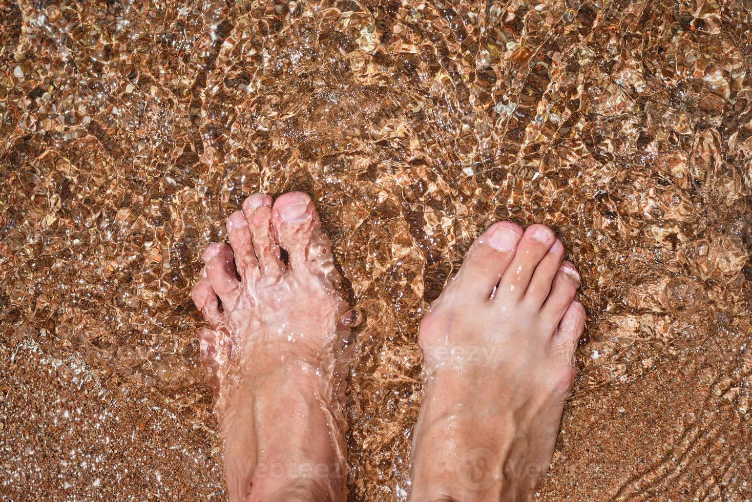 Close up of barefoot legs in the water, top view photo