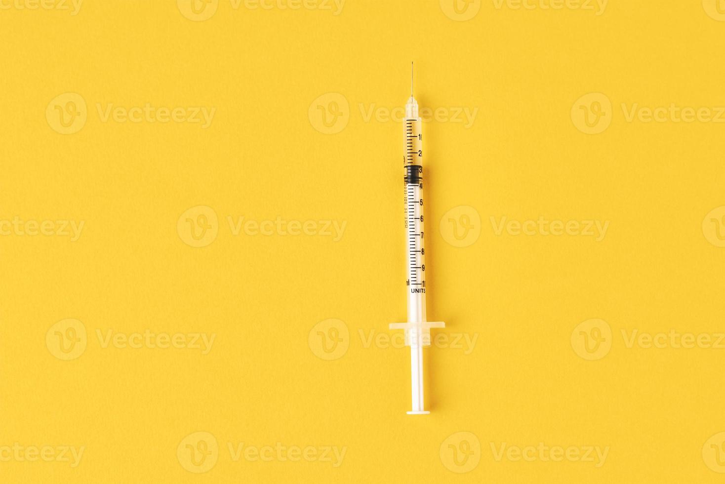 Medical syringe on the yellow background, top view with copy space. photo