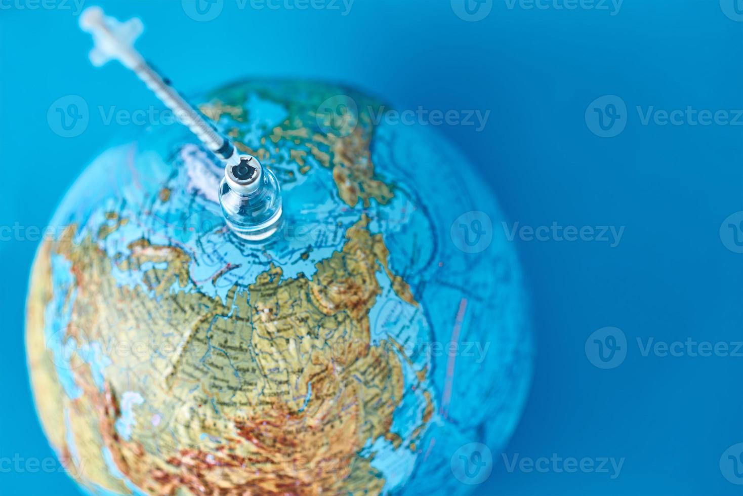 Medical syringe and ampoule with a medicine against Earth globe photo