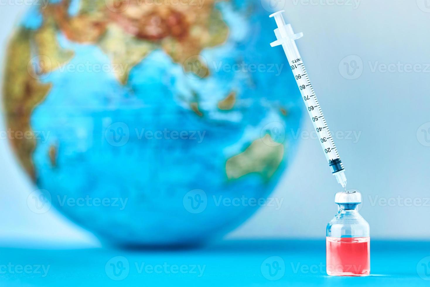 Medical syringe and ampoule with a medicine against Earth globe photo