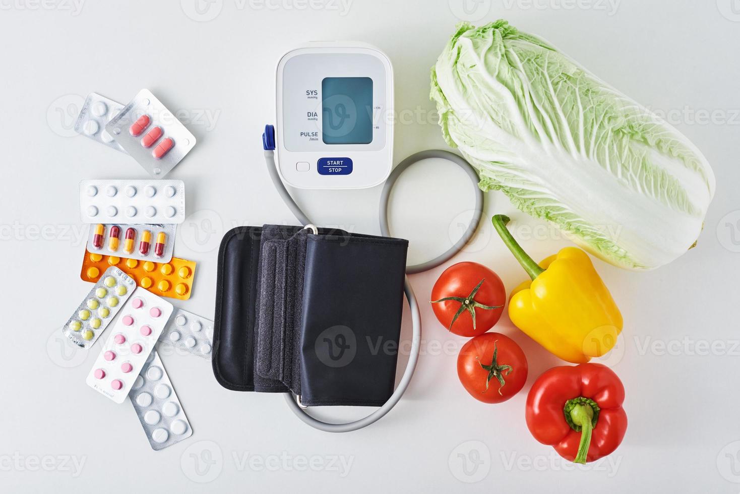 Digital blood pressure monitor, fresh vegetables and medical pills photo