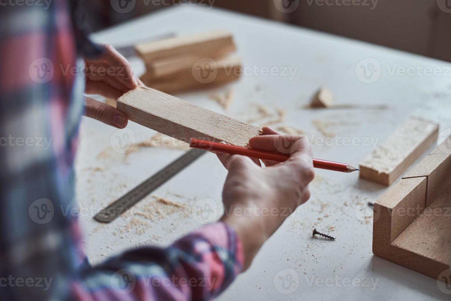 manos de carpintero tomando medidas con un lápiz de tablón de madera. foto