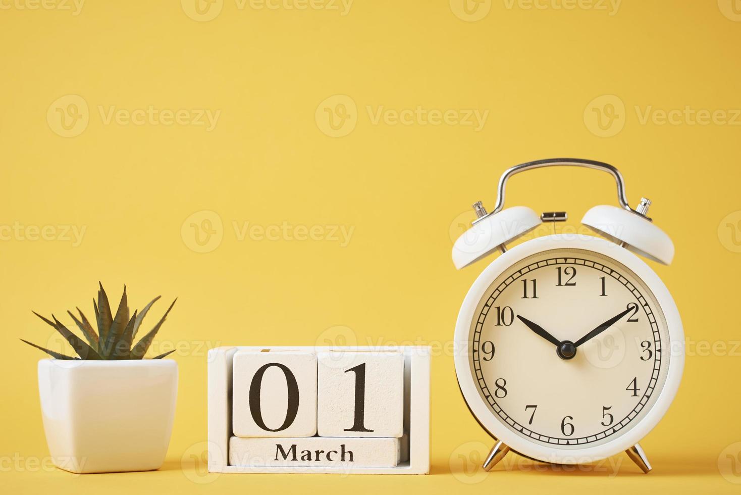 Alarm clock and wooden calendar blocks on the yellow background. Time concept photo