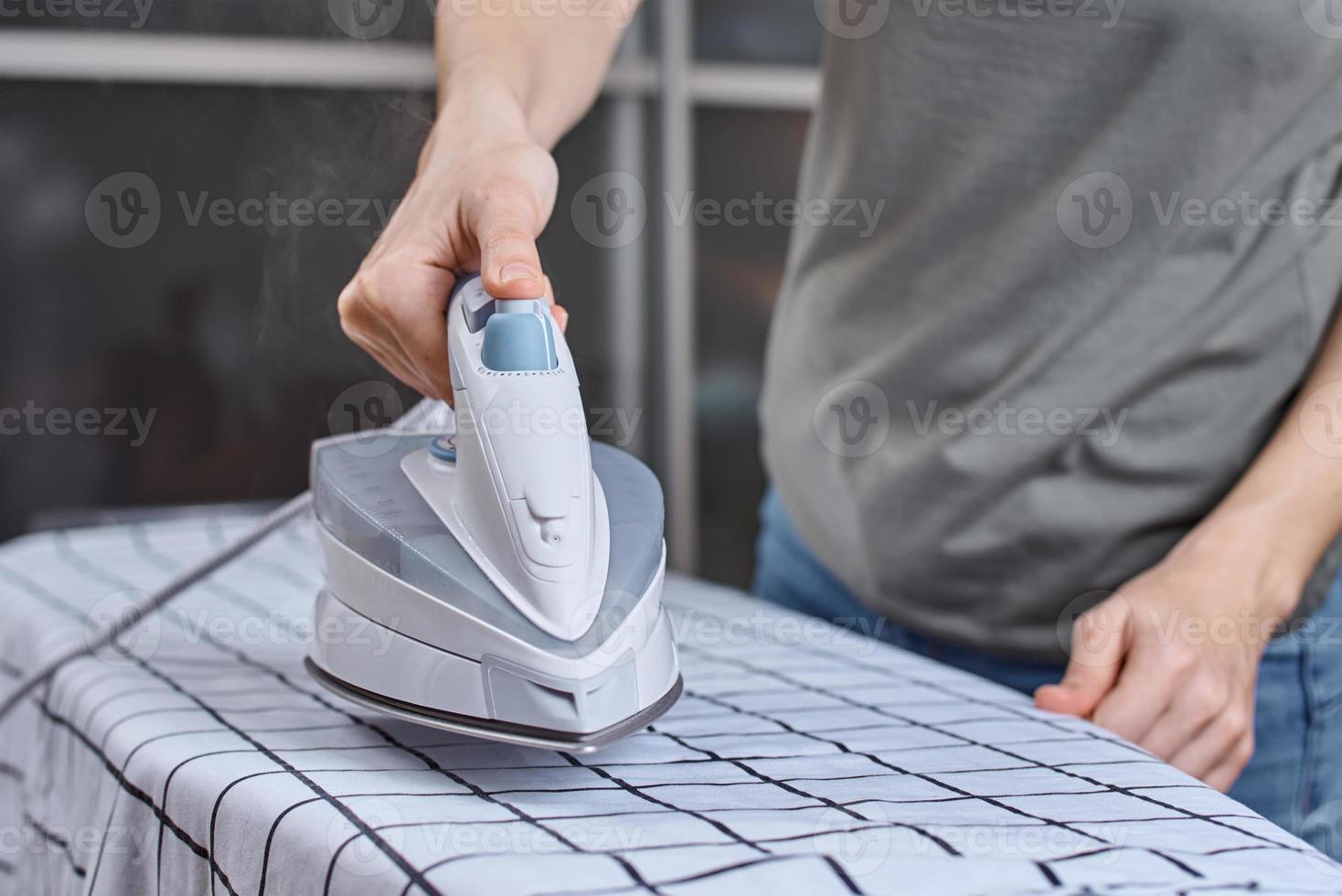 mujer planchando ropa en la tabla de planchar con plancha moderna foto