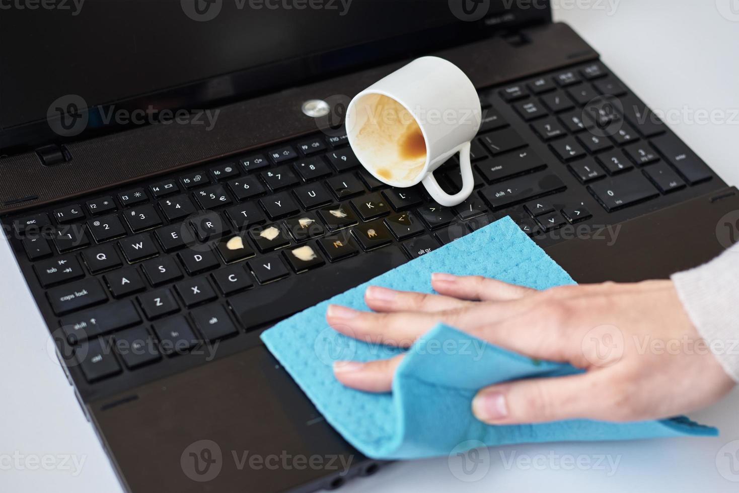 Hand cleans spilled coffee on laptop keyboard with a rag 14264680 Stock Photo at Vecteezy