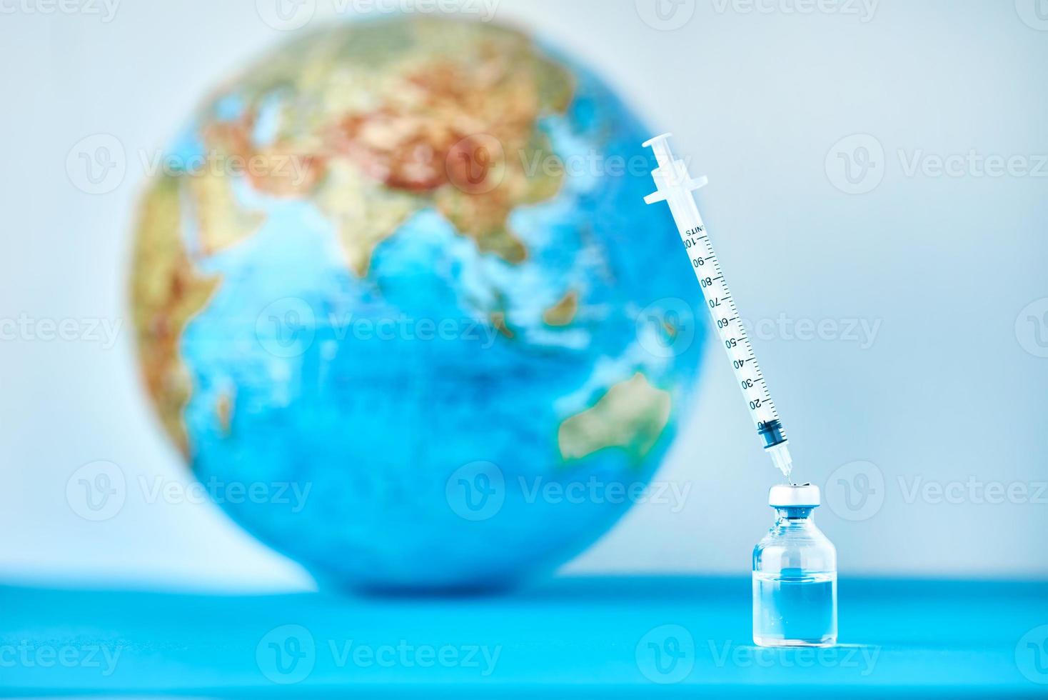 Medical syringe and ampoule with a medicine against Earth globe photo