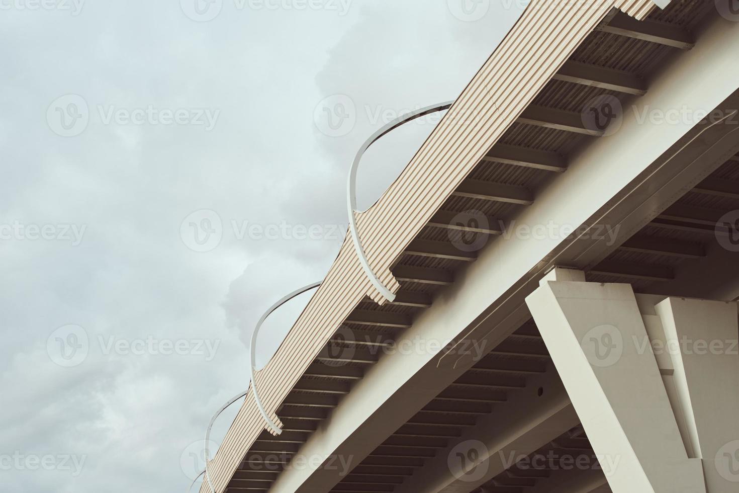 parte del puente moderno con luces de calle contra el cielo nublado foto