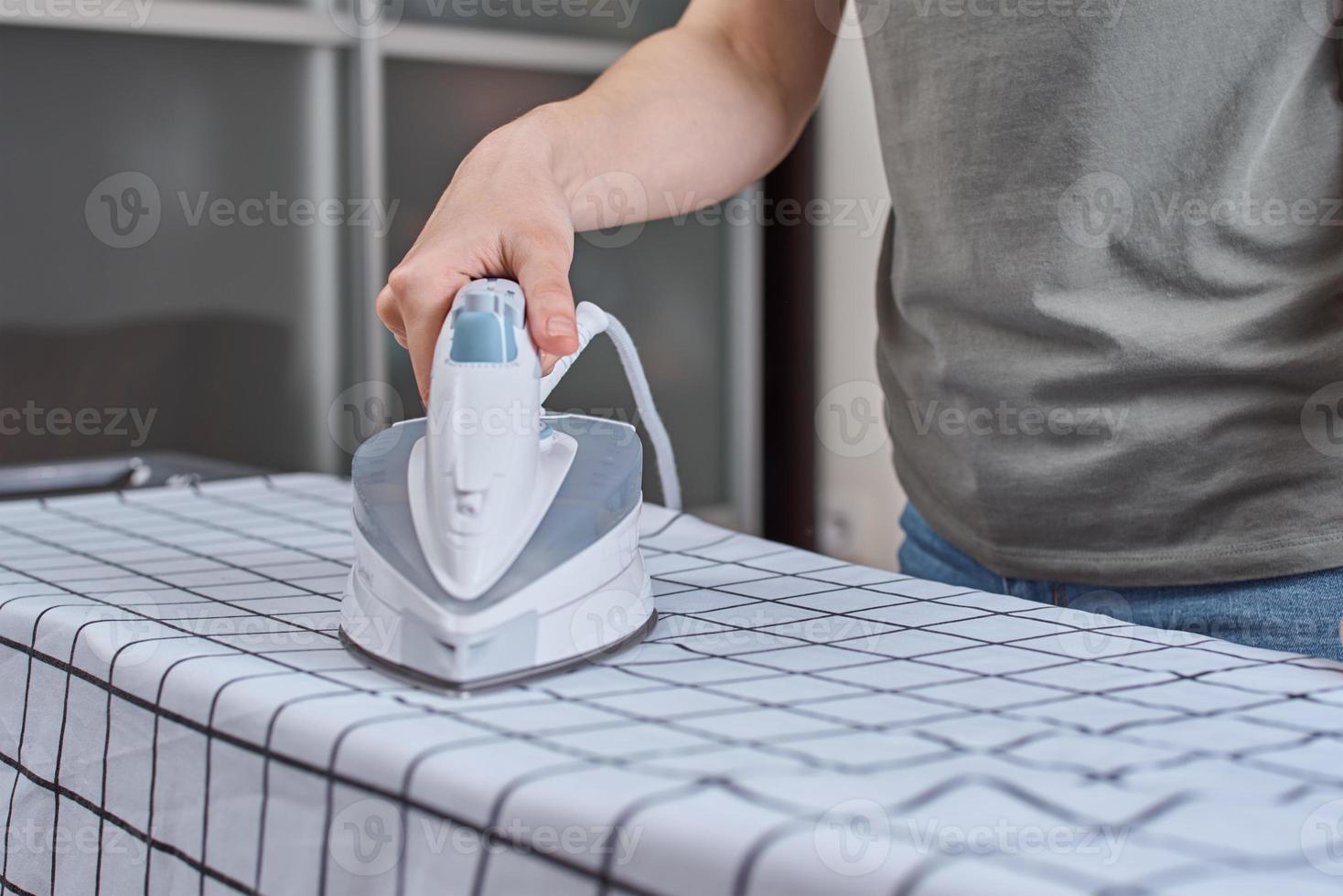 Woman ironing clothes on the ironing board with modern iron photo