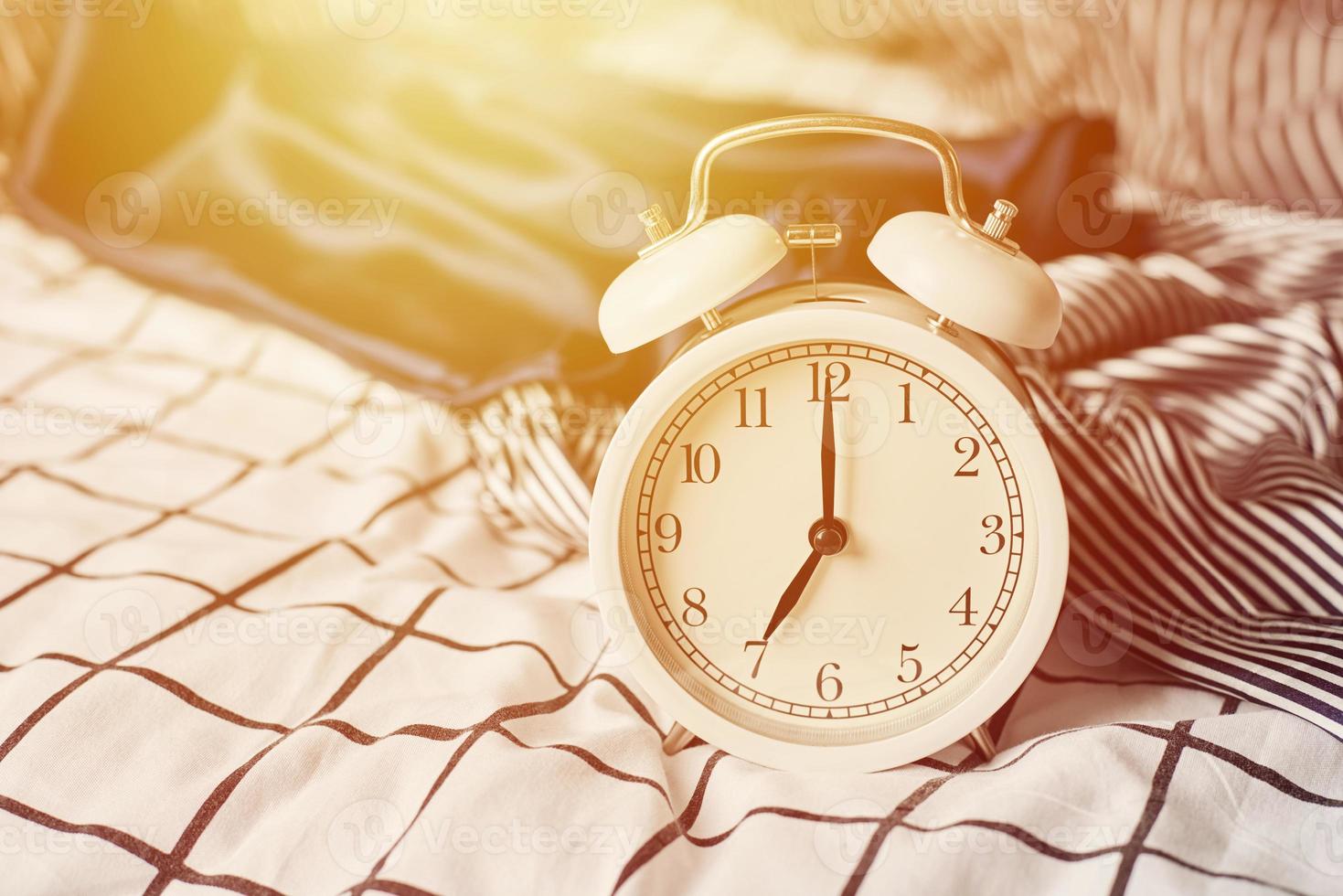 White vintage alarm clock and pillows in the bed. Wale up and morning concept photo