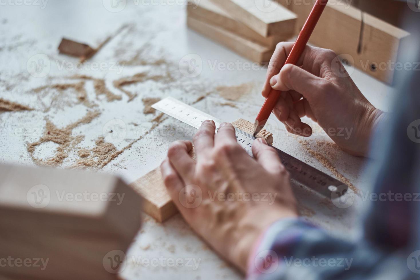 Carpenter hands taking measurement with a pencil of wooden plank. photo