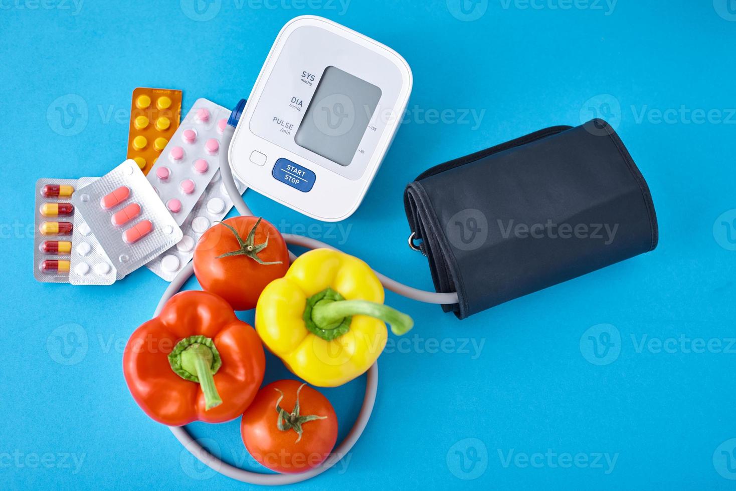 Digital blood pressure monitor, fresh vegetables and medical pills photo