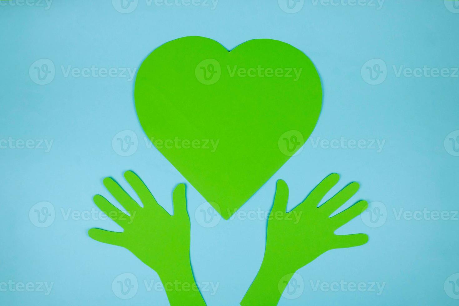 Paper green hands support a paper green heart. The concept of environmental protection photo