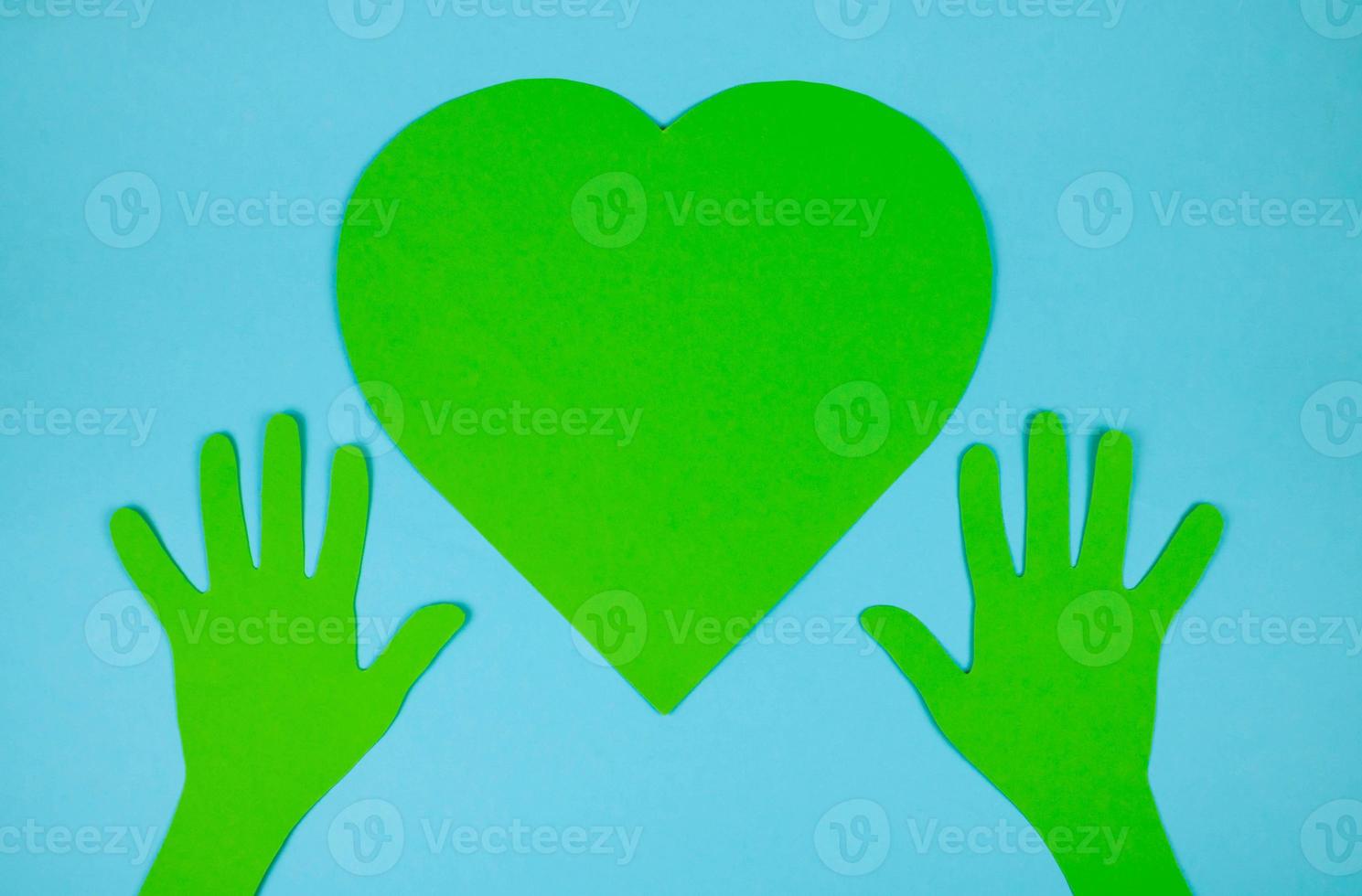 Paper green hands support a paper green heart. The concept of environmental protection photo