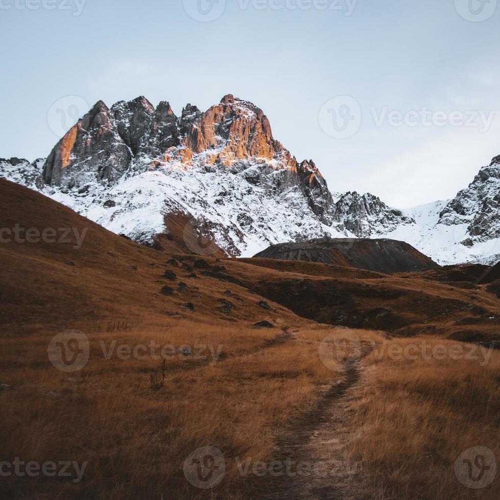 hermosa ruta de senderismo por el valle de juta con fondo de pico nevado de montaña escénica. paisaje del parque nacional de kazbegi foto