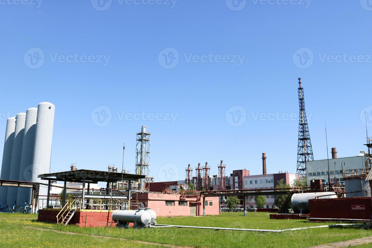 A large concrete technological industrial installation at a chemical petrochemical refinery with capacitive pipes by pumps compressors heat exchangers by pipelines and buildings photo