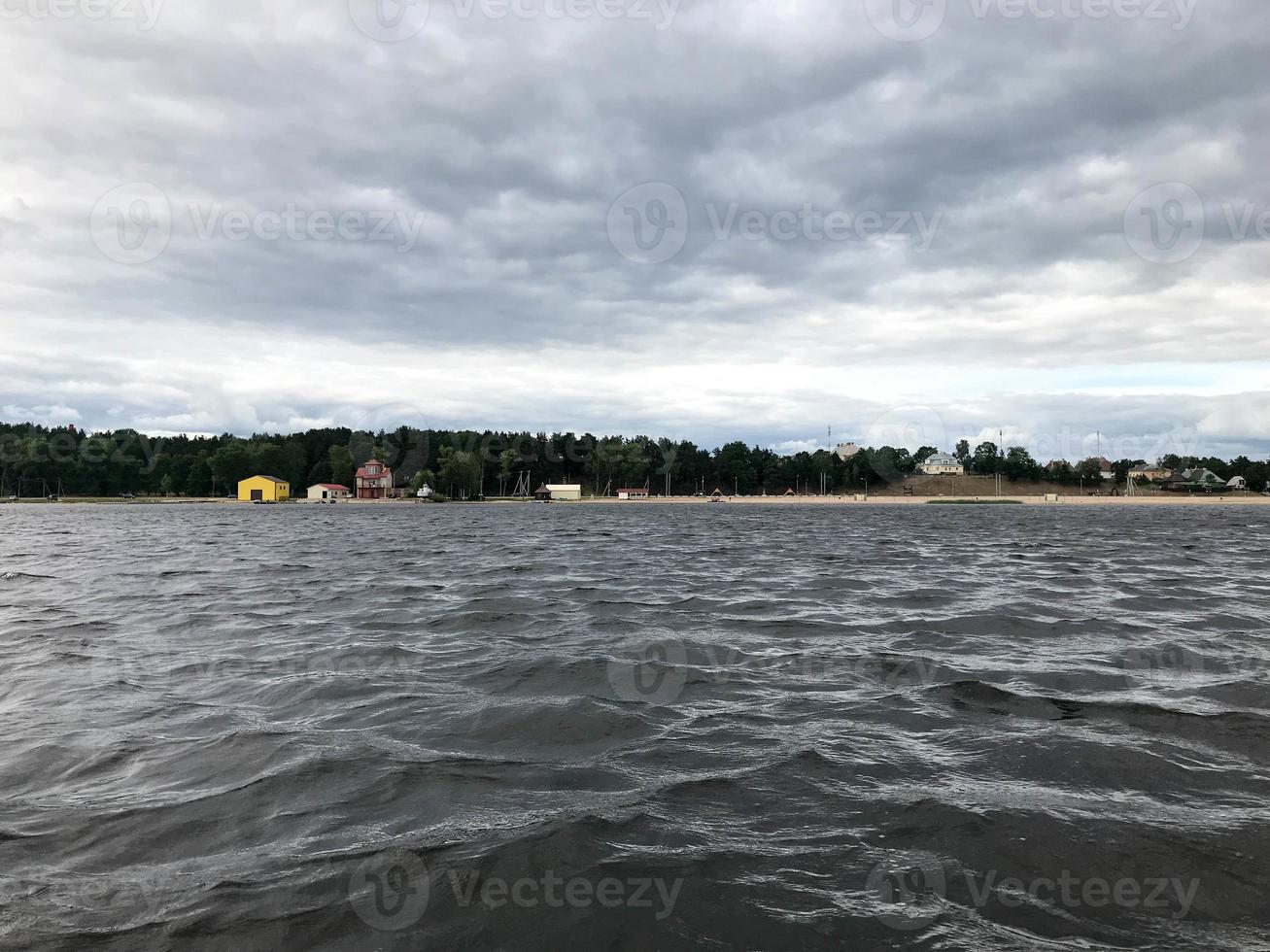 paisaje de la naturaleza de la línea del horizonte con vistas a la orilla, agua con olas desde el medio del lago en el clima frío y nublado foto