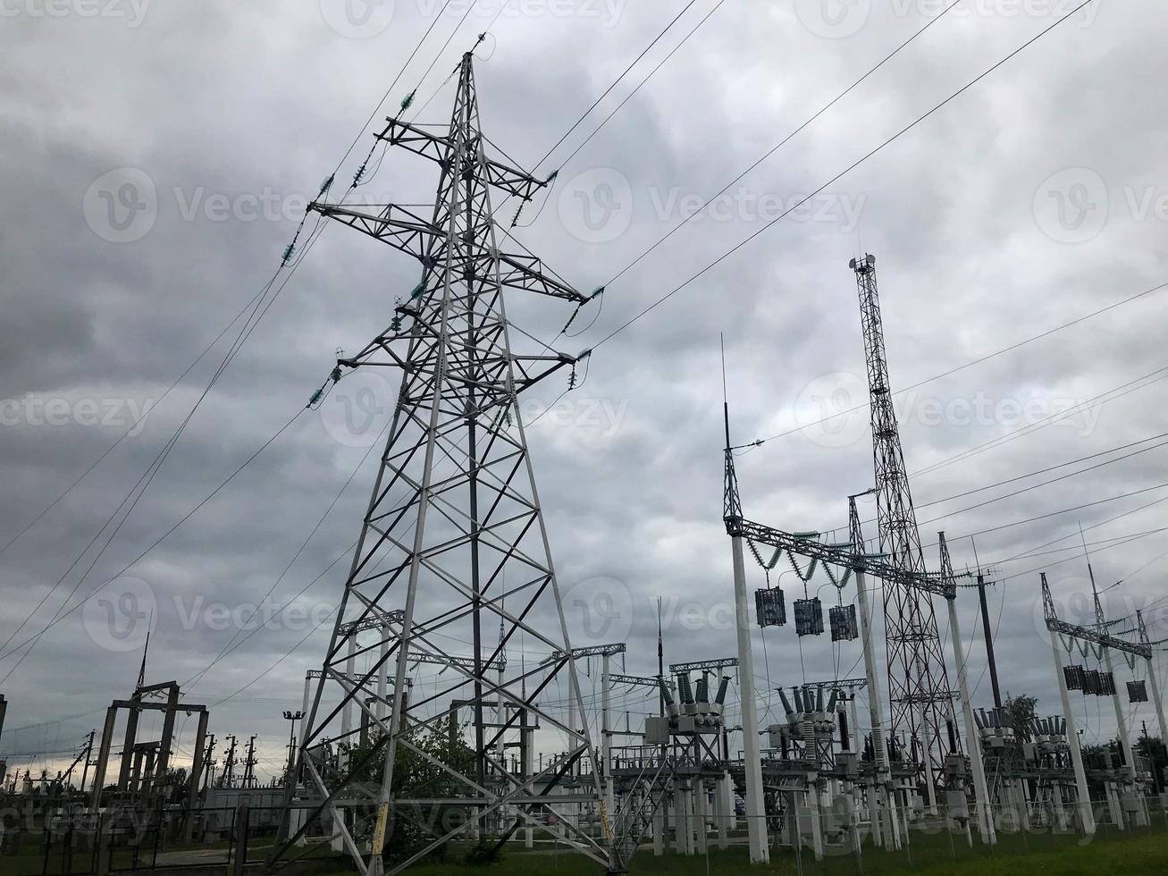 Power equipment of a power plant with a high-voltage line of wires and a transformer substation against a cloudy cloud background photo