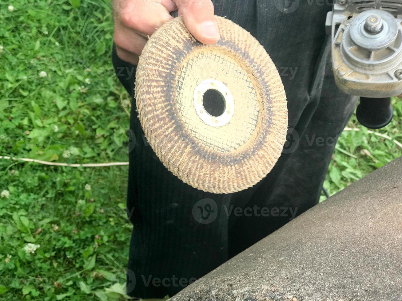 A man holds in his hand a disk of a circle used for a grinding machine for grinding and polishing surfaces from various materials wood, metal, plastic, stone photo