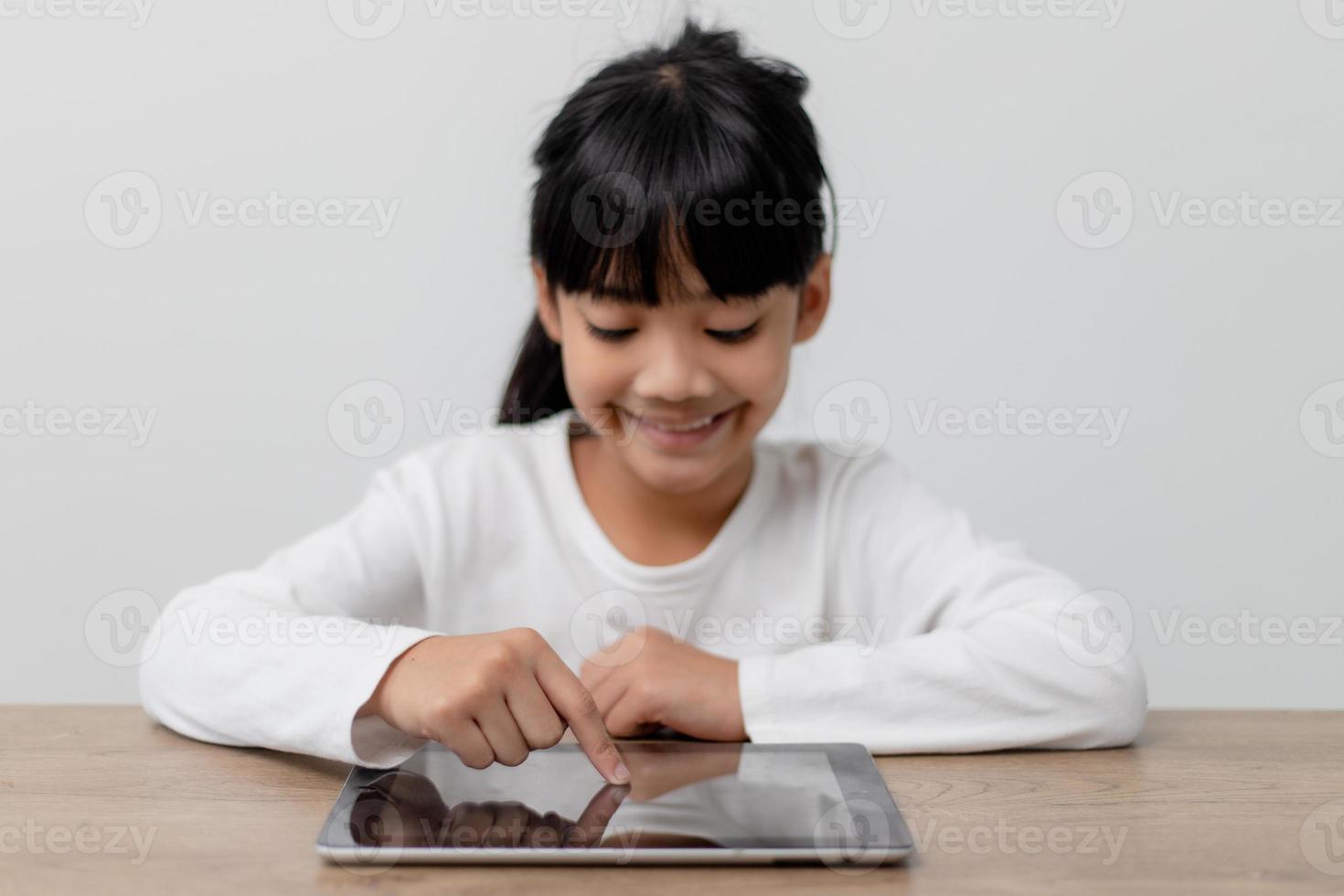 Asian little cute girl touching the digital tablet screen on the table photo