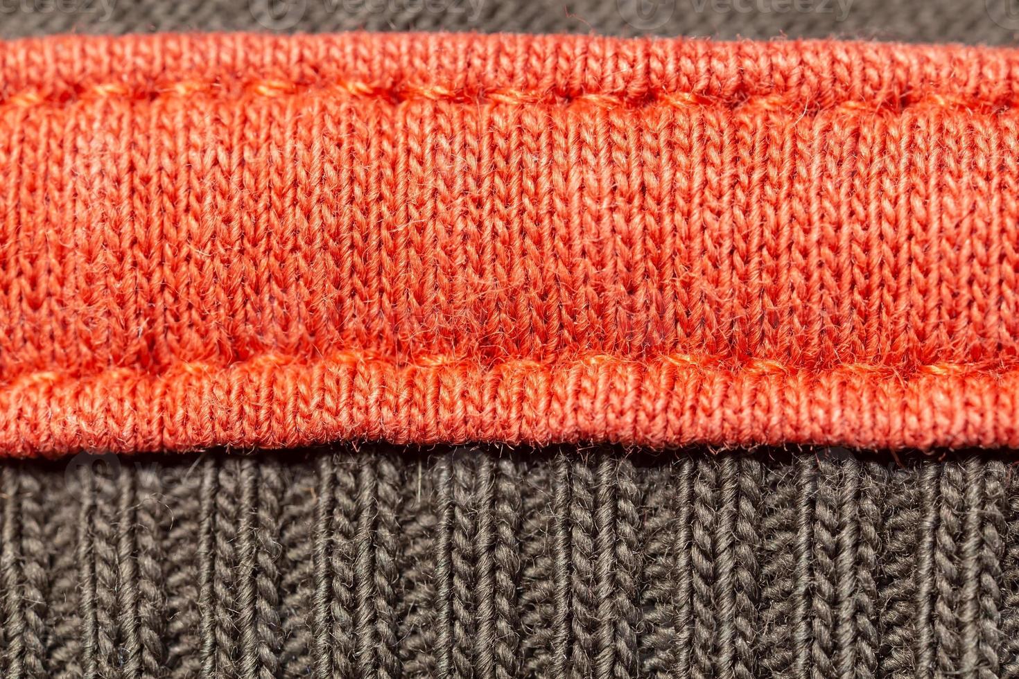 Bright knitted garment with seams, orange and gray. Copy space. Macro. Background. photo