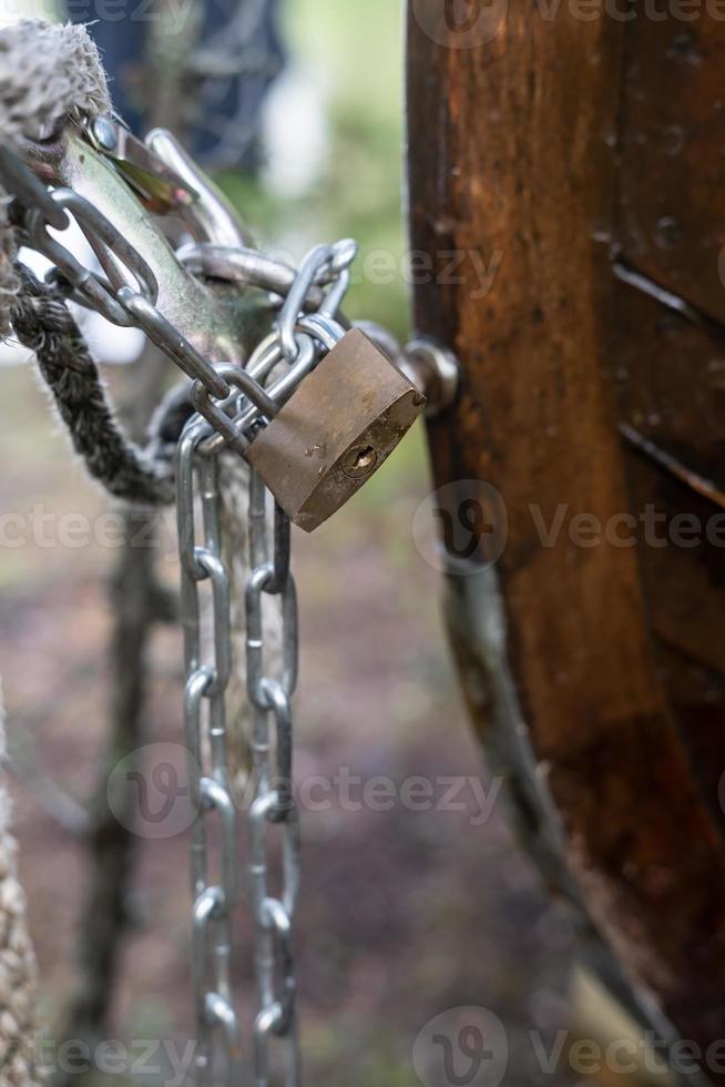 Metal padlock and chain protect private property from theft, in the blurry background. Close-up. photo